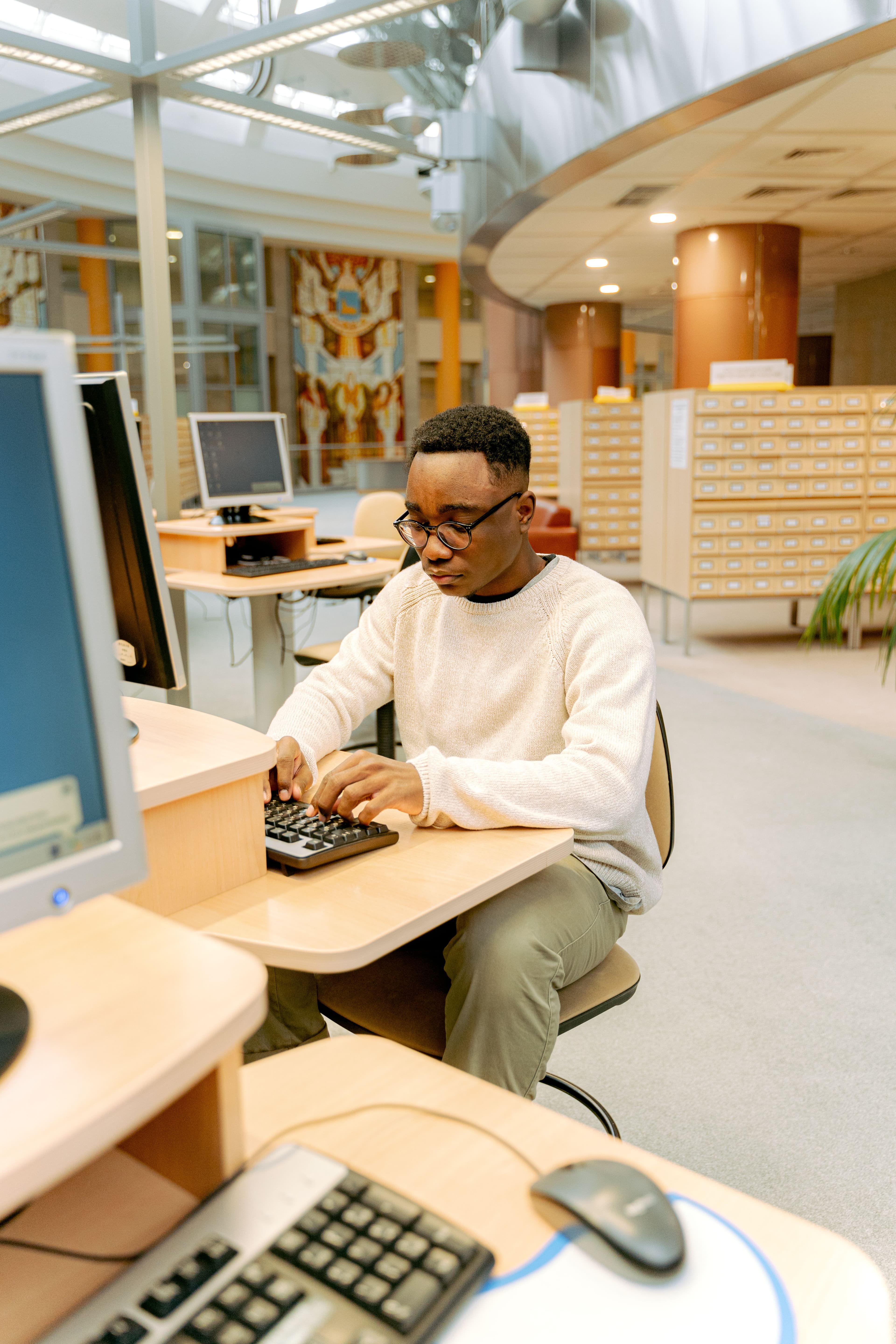 Étudiant travaillant sur ordinateur dans une bibliothèque